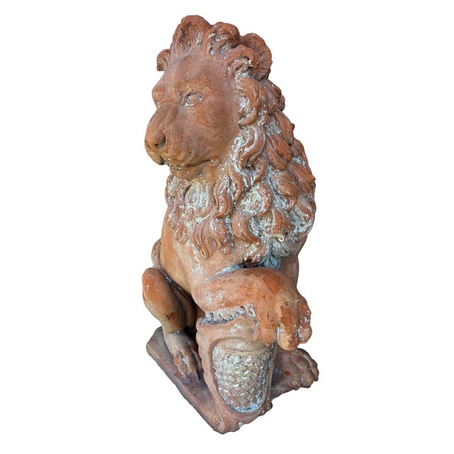 Pair of Italian terracotta lions seated with their paw resting on a crest. From the founder of Yankee Candles Estate.