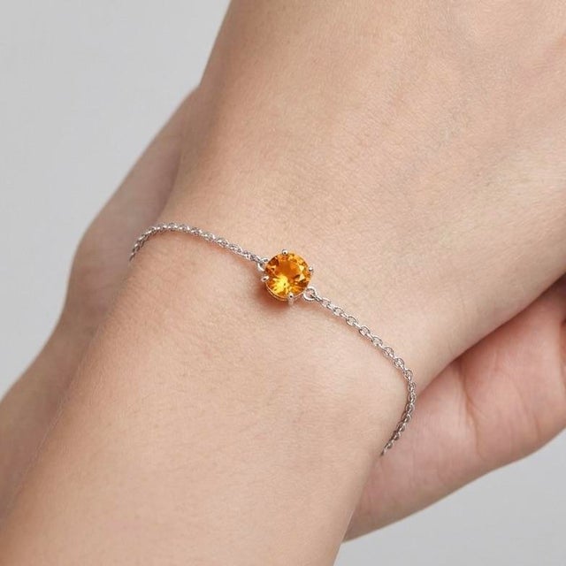 Delicate and radiant, this elegant bracelet features a single golden gemstone gracefully set on a fine silver...