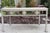 Charming vintage coastal bench featuring a sculptural frame adorned with repeating scallop shell motifs and a richly...