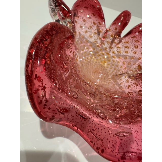 Sculptural hand-blown art glass bowl in rich cranberry pink with a dramatic ruffled freeform rim. The glass is heavily...