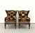 A distinctive pair of carved wood wingback armchairs upholstered in patchwork cowhide in rich shades of brown, black, tan,...