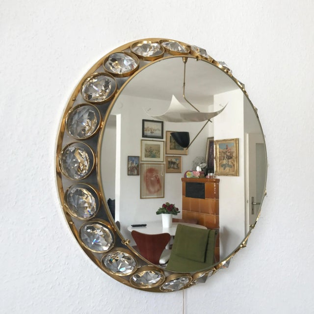 This decorative mid-century Modern illuminated wall mirror features a brass frame and large crystal elements. The piece is...