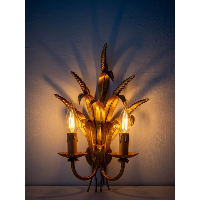 A sculptural trio of italian gilt iron wheat sheaf wall sconces in the hollywood regency tradition, each with twin candle...