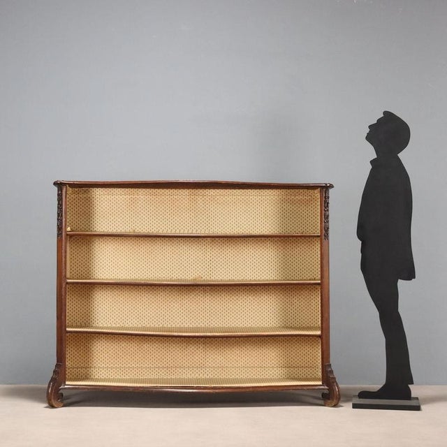 Baroque-style open bookcase in walnut and walnut burl. Curved front, 45° uprights with leaf carvings and scrolls, paneled...