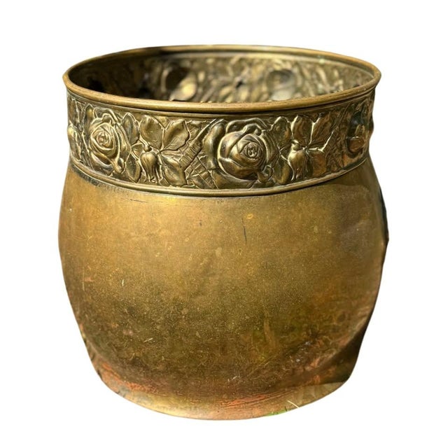 A beautifully scaled indoor or outdoor antique brass jardinière cachepot featuring richly detailed repoussé floral...