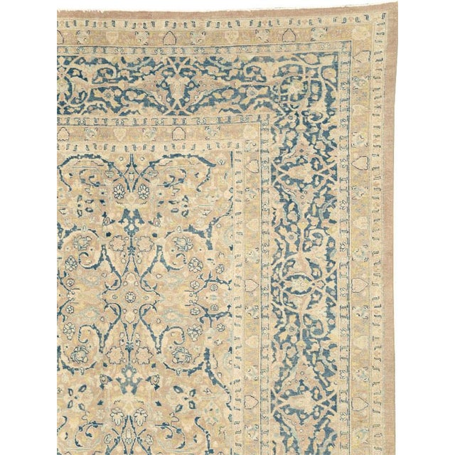 This early 20th-century Persian Tabriz carpet presents an elegant allover floral composition across a warm ivory and soft...