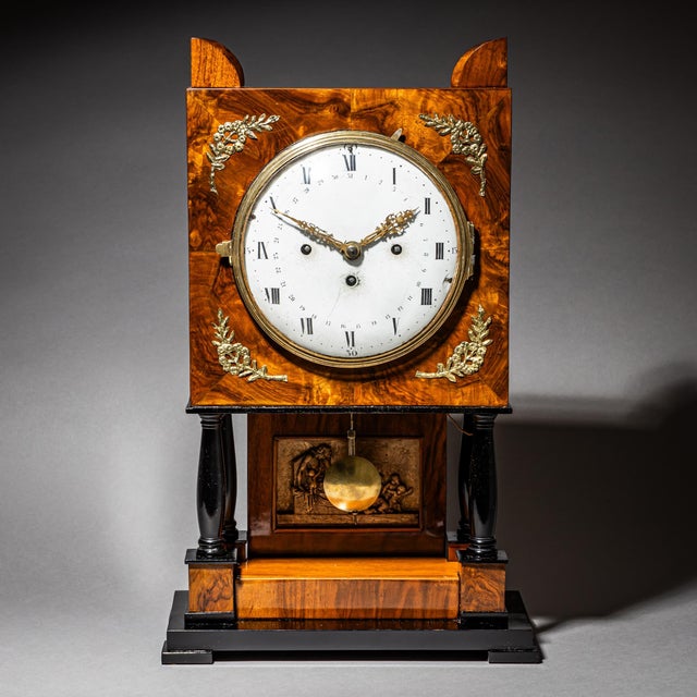Bracket clock in a walnut case with ebonized columns and base. The case is decorated with brass appliqués. The movement...