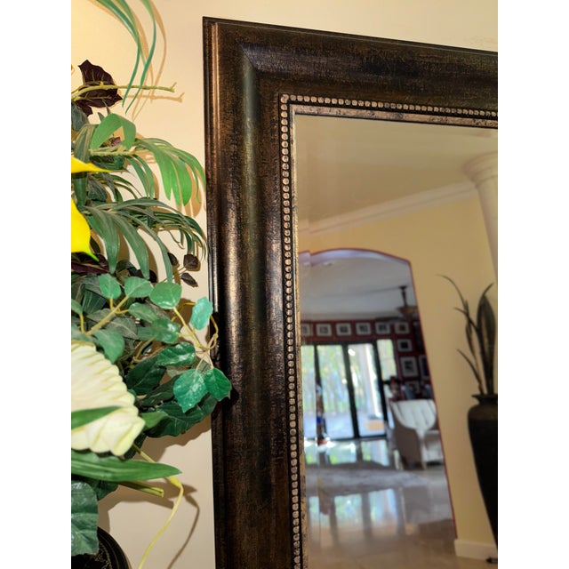 Gorgeous oversized floor mirror with an elegant antique gold carved wood frame. This piece features rich detailing on the...