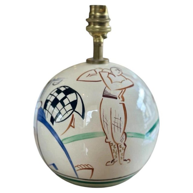 Hand-painted golfers, a caddy and golf bags wrap around the spherical body of this Gray’s Pottery lamp. The cream glaze...