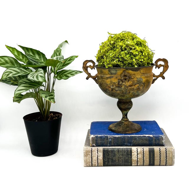 Gorgeous, mid to late 20th century brass pedestal urn featuring an antiqued verdigris finish and a classic Neoclassical...