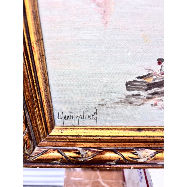 This framed maritime oil painting depicts a tranquil harbor scene with fishing boats moored by a pier and a small rowboat...