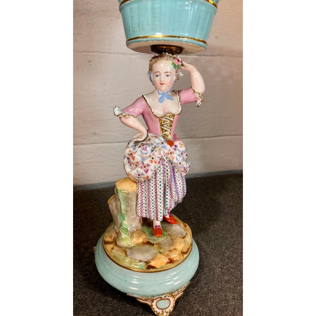 Depicting a Lady, likely a shepherdess or noblewoman, carrying an open-weave basket on her head. Hand-painted porcelain...