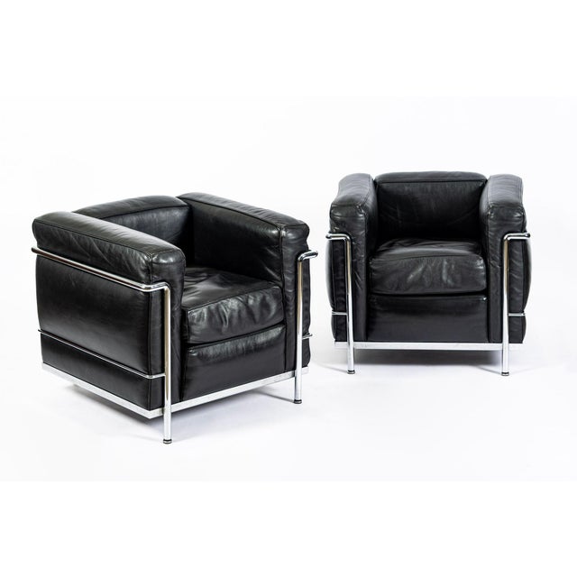 This matching pair of authentic LC2 Petit Modele black leather armchairs originally designed by Le Corbusier, Charlotte...