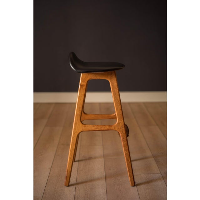 Mid Century Modern counter stool in teak designed by Erik Buch for O.D. Mobler. Features a black vinyl seat equipped with...