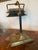 Vintage banker's lamp, featuring a distinctive design with a brass "hand" detail at the top of the shade. Shade is...