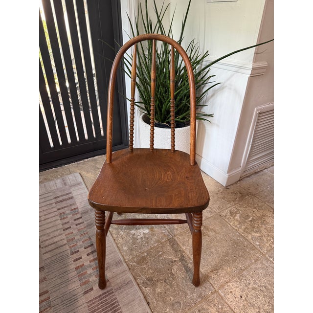 Windsor-style wooden bow back accent chair with turned spindles, a saddle seat and turned spindle legs. Made of solid wood.