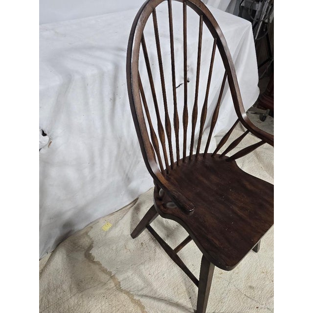 Classic vintage Windsor bow back armchair crafted from solid hardwood with a rich dark finish. This elegant chair features...