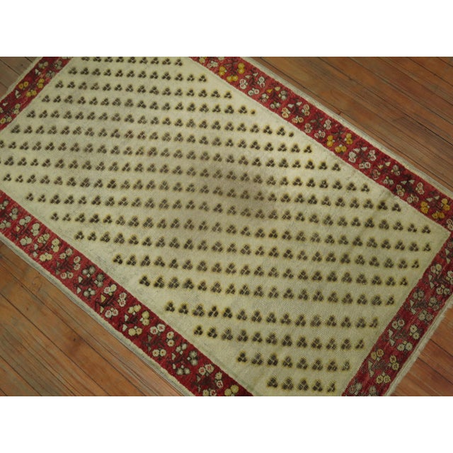 Late 19th century antique Turkish Ghiordes rug. Ivory ground, small repetitive field surrounded by a floral red border 3'...