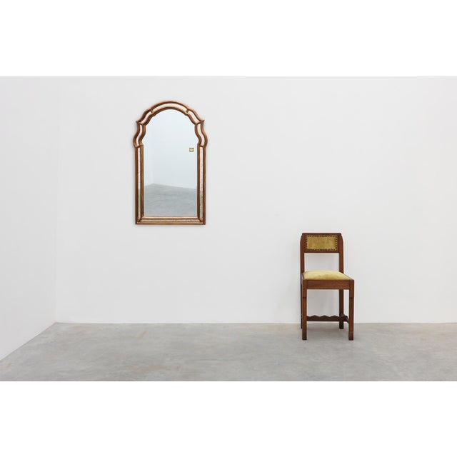 An elegant Belgian wall mirror by Deknudt, distinguished by its refined arched silhouette and richly detailed gold-leaf...