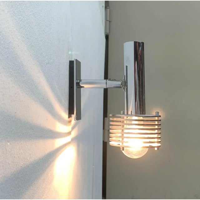 Space Age wall sconce in chrome. A striking detail of this luminaire is the reflector screen that is dissolved in slats....