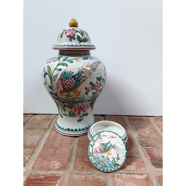 A set of two hand painted jars from Portugal. The first is a traditional shaped ginger jar with a colorful exotic bird and...