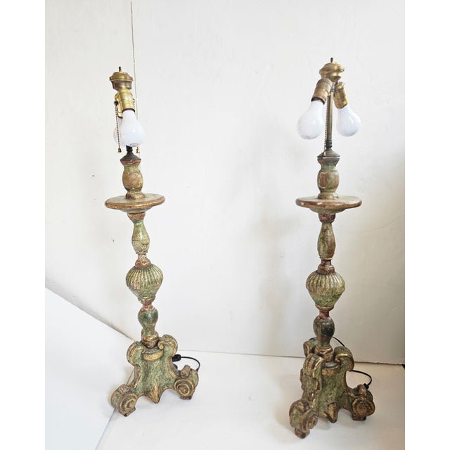 Characterful antique pair of candlestick table lamps having carved wood weathered painted & gilded forms. Intentionally...