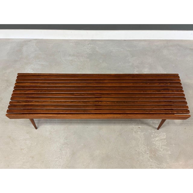 A mid century modern slatted bench or coffee table made of solid beech in a rich walnut colored stain. Professionally...