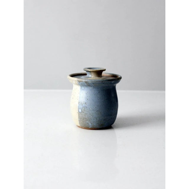 This is a vintage studio pottery jar dated 1984. Signed by the artist (Palmer), the jar features a cream and blue speckled...
