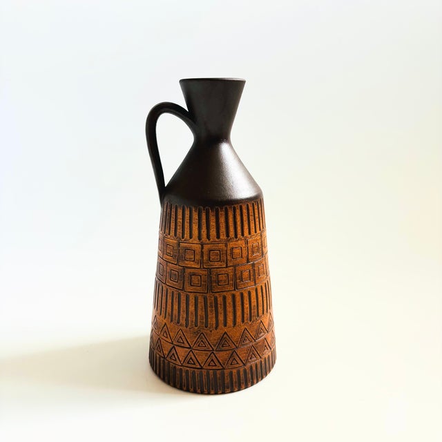 A mid century German pottery vase. Features a handle on one side and tone glazes in dark brown and terra corra with a...