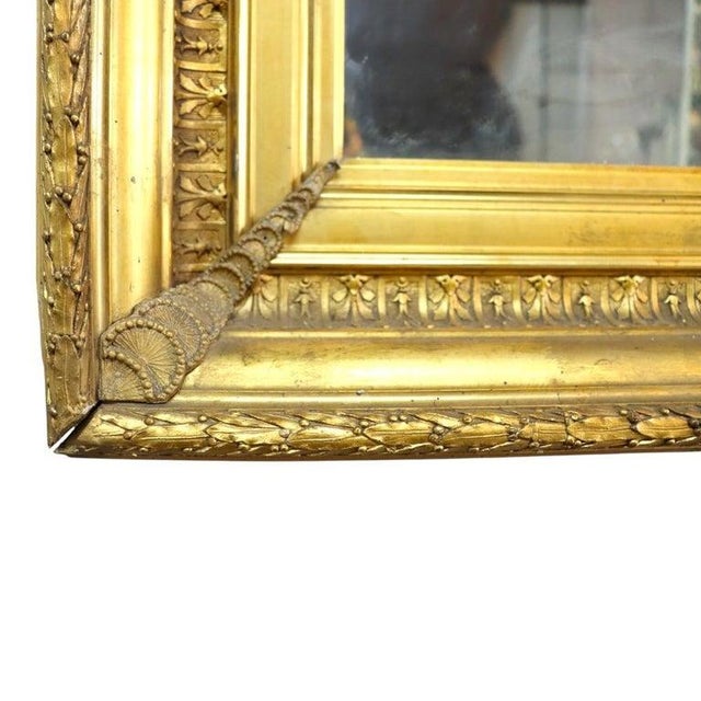 This oversized antique mirror features a meticulously crafted gilt wood frame, dating to approximately 1890. The frame is...