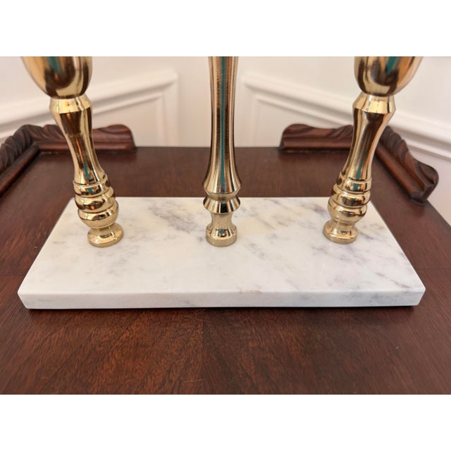 Striking three-candle candelabra featuring sculptural brass candleholders mounted on a substantial rectangular white...