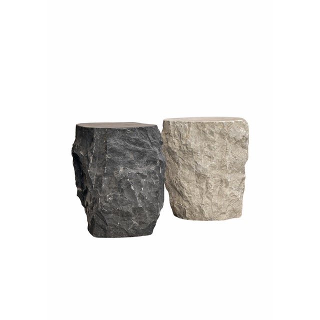 Carved from solid dark marble, this sculptural side table embodies a raw, monolithic presence defined by natural texture...