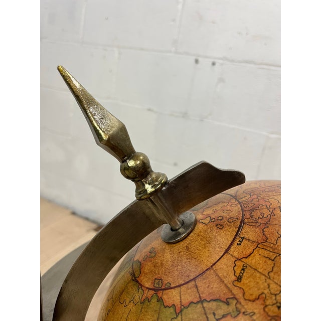 A distinctive vintage Hollywood Regency globe side table crafted from sculptural steel and brass with a circular glass...