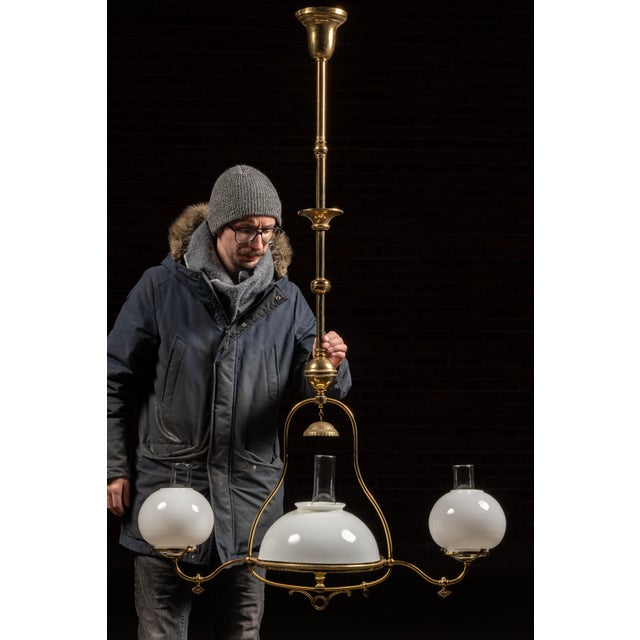 This late-19th-century brass gas fixture reflects the transitional engineering found in American interiors as gaslight...