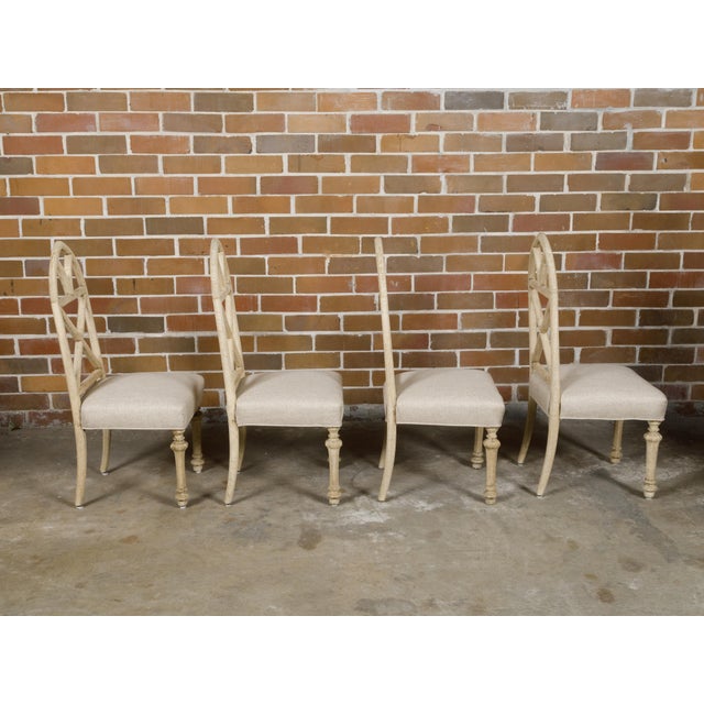 A set of four English Gothic Revival bleached oak dining room chairs with broken arch backs, faceted tapering legs and...