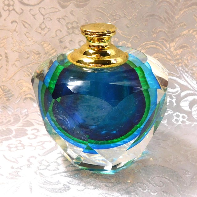 This is a clear faceted crystal perfume bottle with a blue and green bottle inside. The bottle has a metal neck with a...
