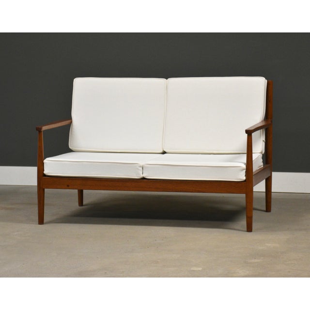 A mid century modern solid teak loveseat sofa. Well made professionally refinished. New white cushions. Seat height is...