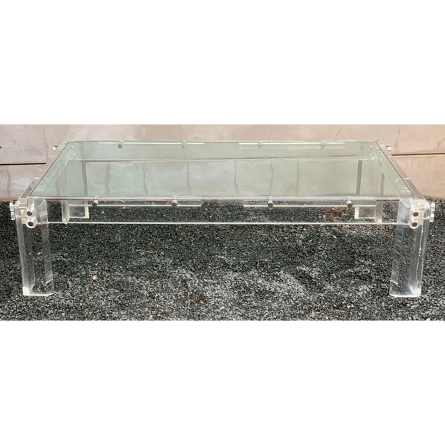 Large-scale vintage Lucite and glass coffee table, circa 1970s, featuring a thick tempered glass top floating within an...