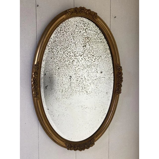 A antique oval mirror ca 1900, gilt with a mercury plate. It displays a beautiful old patina on the doved frame with...
