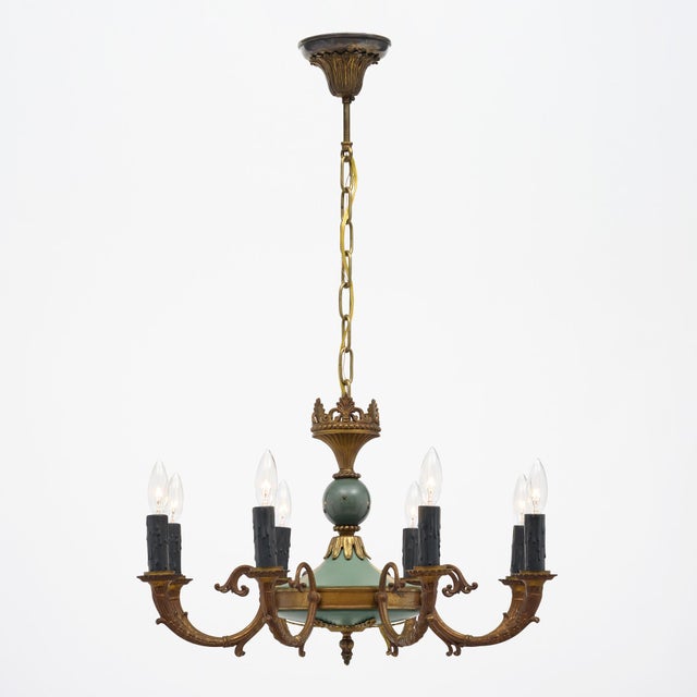 Chandelier from France in the Empire style. Made of painted bronze, this striking piece boasts eight “Cornupia” stylized...
