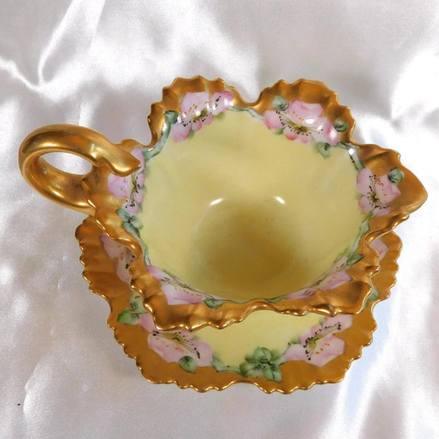 This is a yellow Tressemanes & Vogt Limoges gravy boat with pink flowers and an attached underplate. It is signed B....