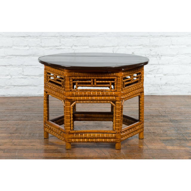 A Chinese Qing Dynasty period coffee table from the 19th century, with black lacquered elm wood top, hexagonal bamboo base...