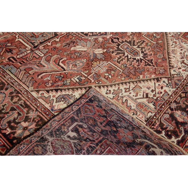 Beautiful antique Heriz hand-knotted wool rug with a rust color field. This Persian rug has gray, peach, and beige accents...