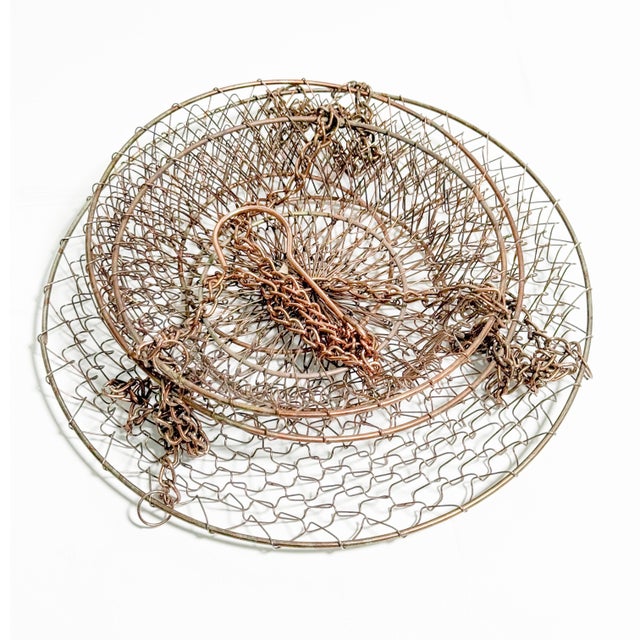 A fabulous vintage three-tier hanging fruit basket featuring warm copper-tone metal, delicate open wire mesh, and three...