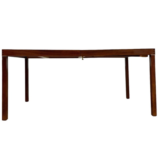 This vintage Mid-Century Modern dining table features a clean, architectural silhouette paired with a practical extensior...