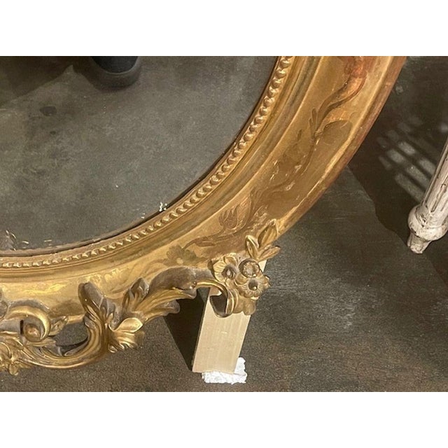 This product is a rare and elegant 19th century French ornately carved giltwood oval mirror. The intricate detailing and...