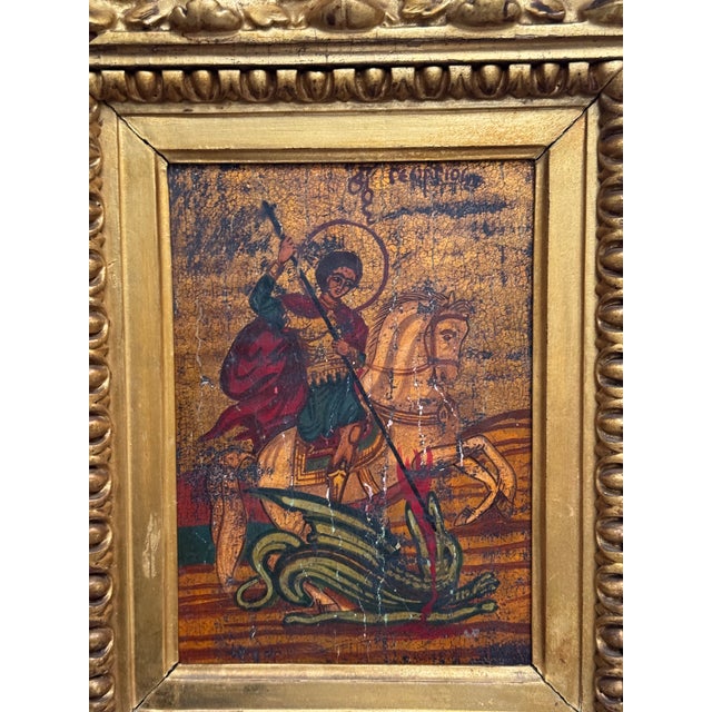 A striking Old World devotional icon depicting Saint George slaying the dragon, hand-painted on a substantial, thick piece...