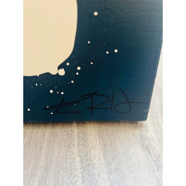 A striking contemporary abstract featuring a bold ivory circular form set against a rich, moody navy ground. The...