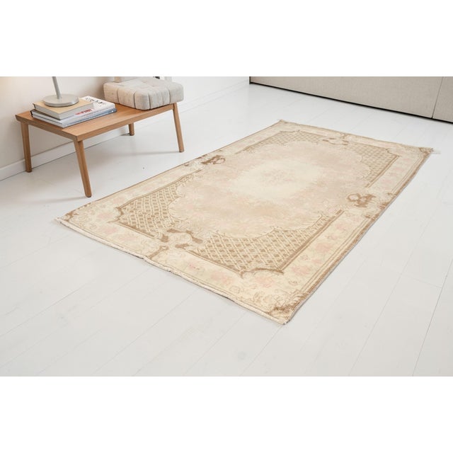 This is a vintage Turkish Oushak rug from the Mid 20th Century. The piece was hand-knotted.