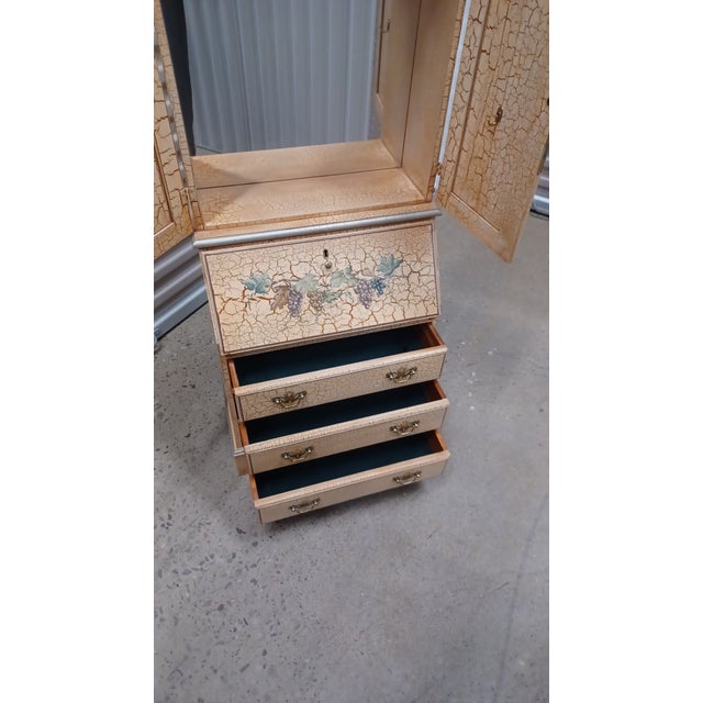 Late 20th century jewelry armoire disguised as a drop down cabinet. Hand painted flowers on a crackle finish give it light...